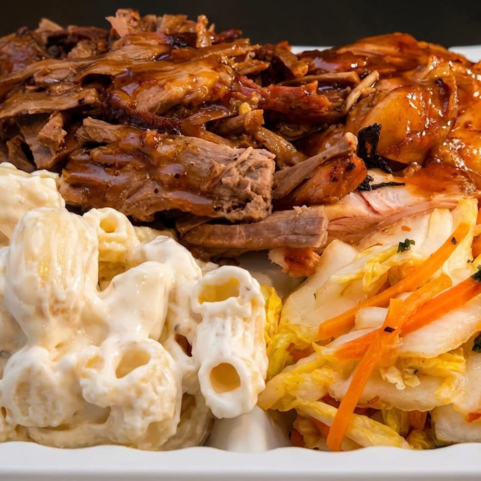 Plate of glazed shredded meat with creamy pasta salad and colorful cabbage-carrot slaw.