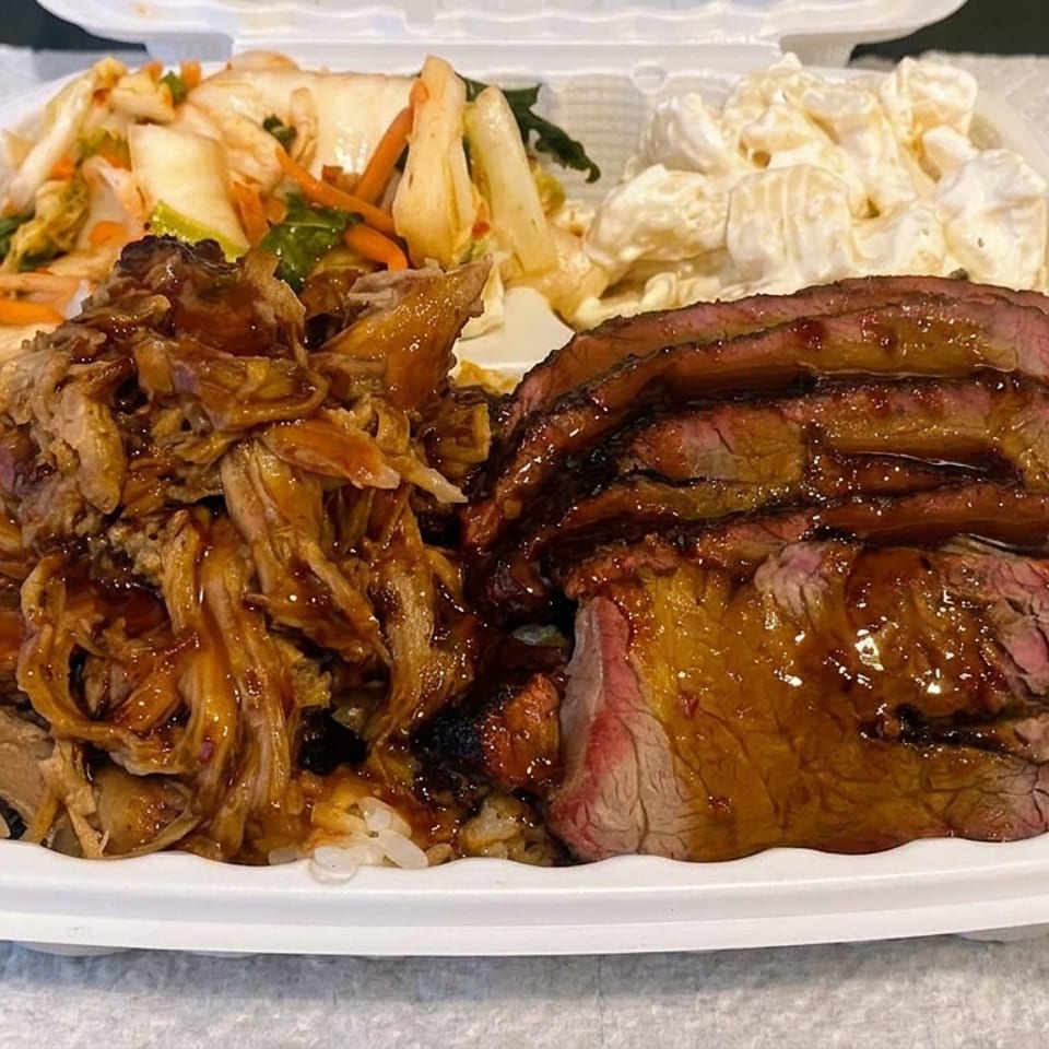 Takeout container filled with sliced glazed beef, shredded meat, rice, mixed vegetables, and creamy macaroni salad.